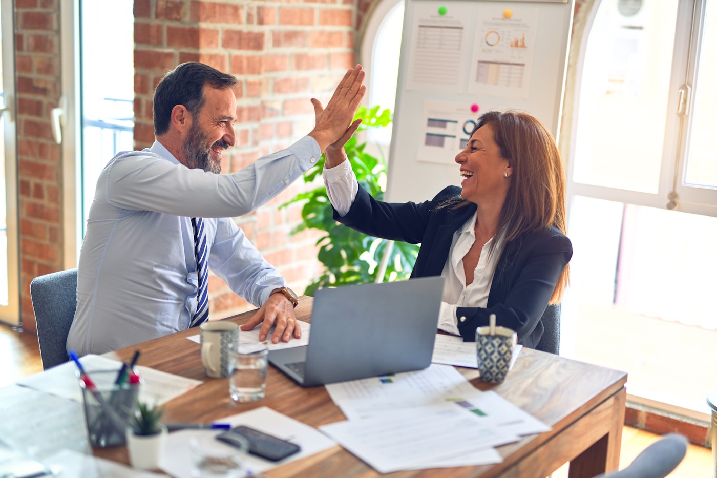 Two colleagues high-fiving in a bright office