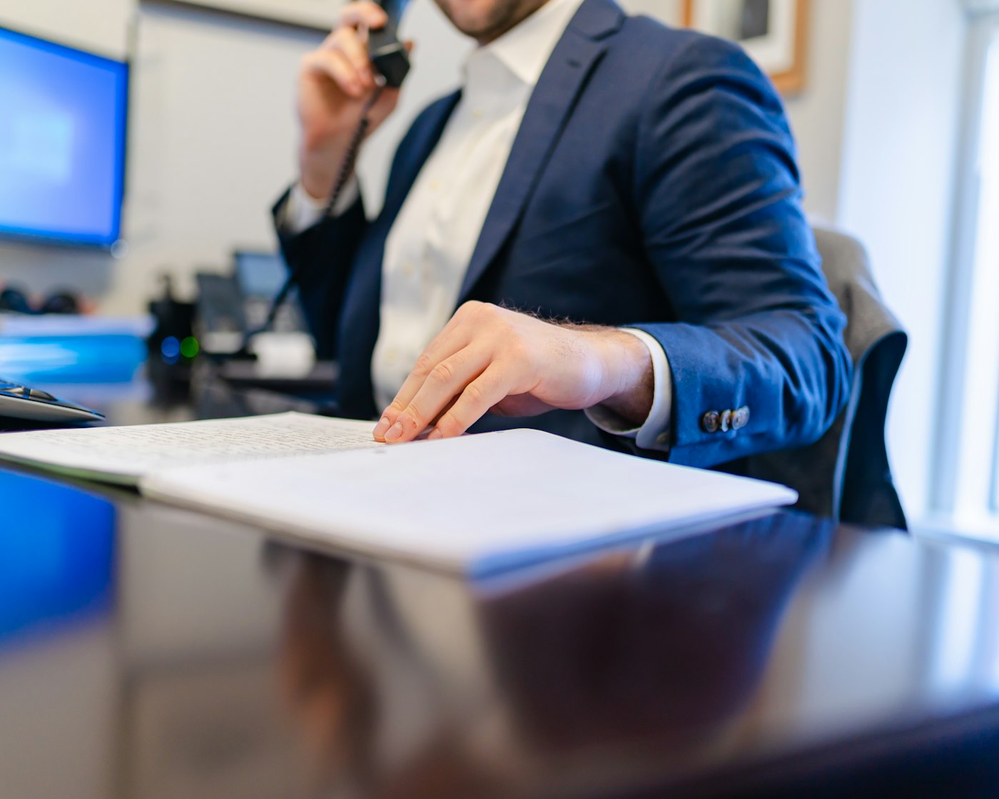 Insurance agent on the phone reviewing paperwork, the kind of renewal question a virtual assistant for insurance agencies answers first