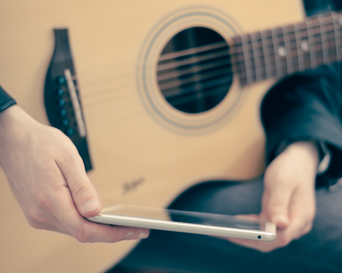 Musician checking phone with guitar in hand, backed by a virtual assistant for musicians