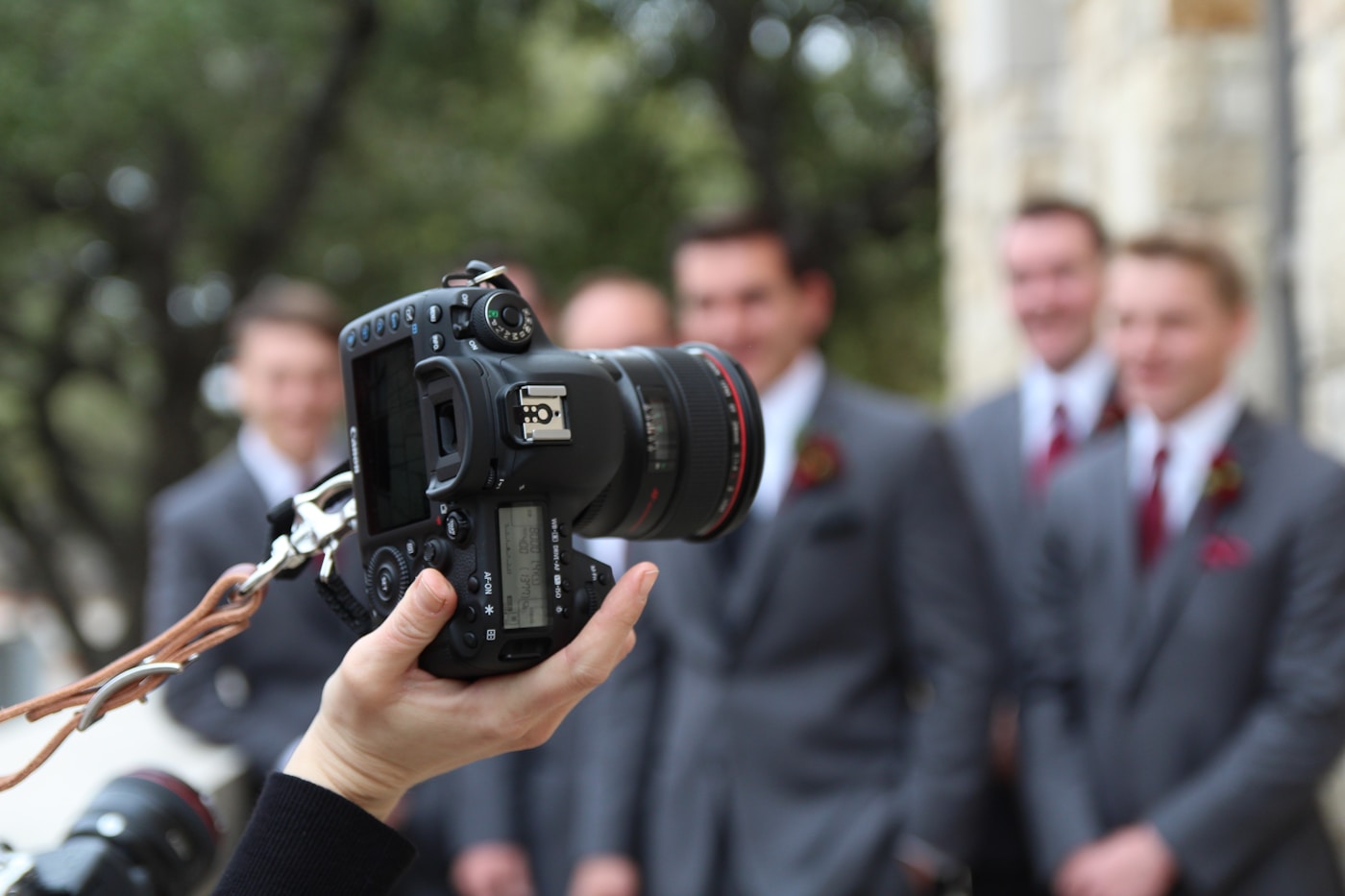 Wedding photographer checking phone between shots, using a virtual assistant for wedding photographers to catch inquiries